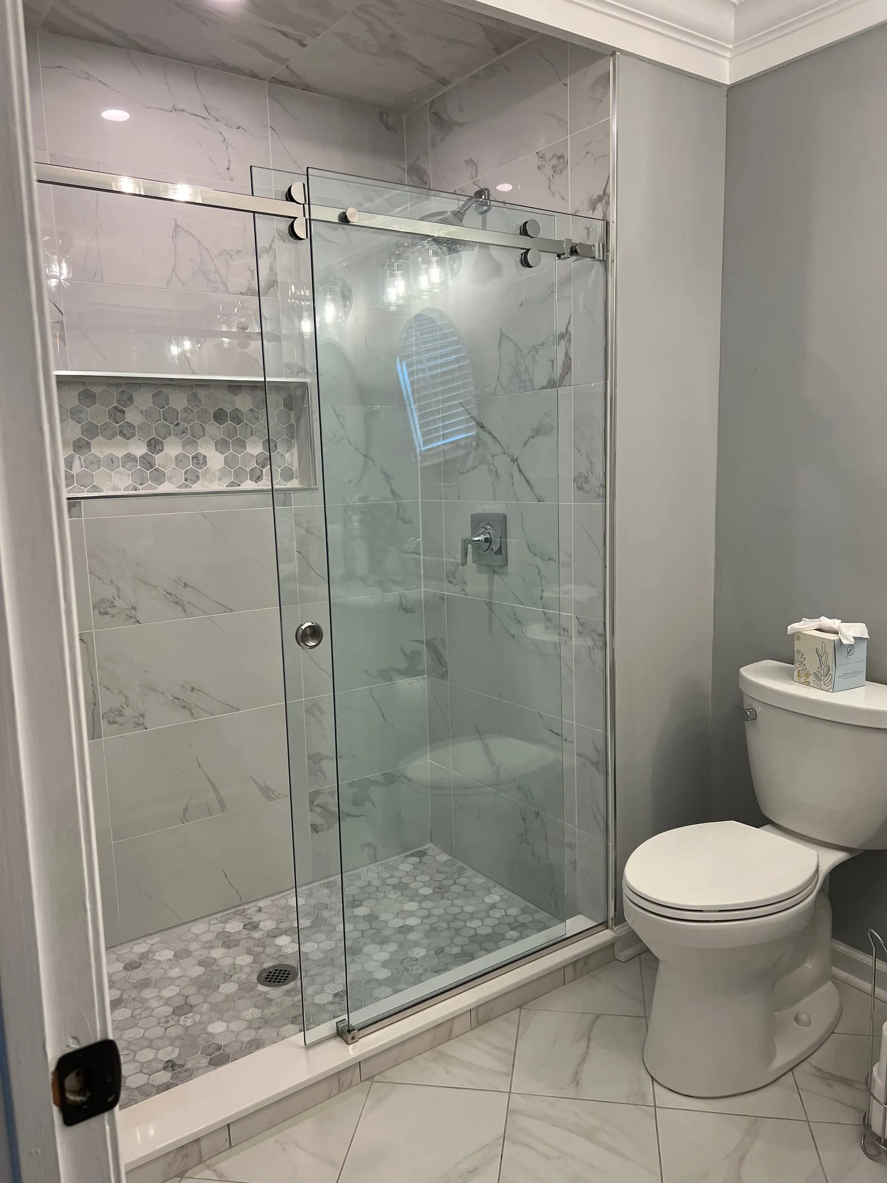 A marble shower with a frameless glass door