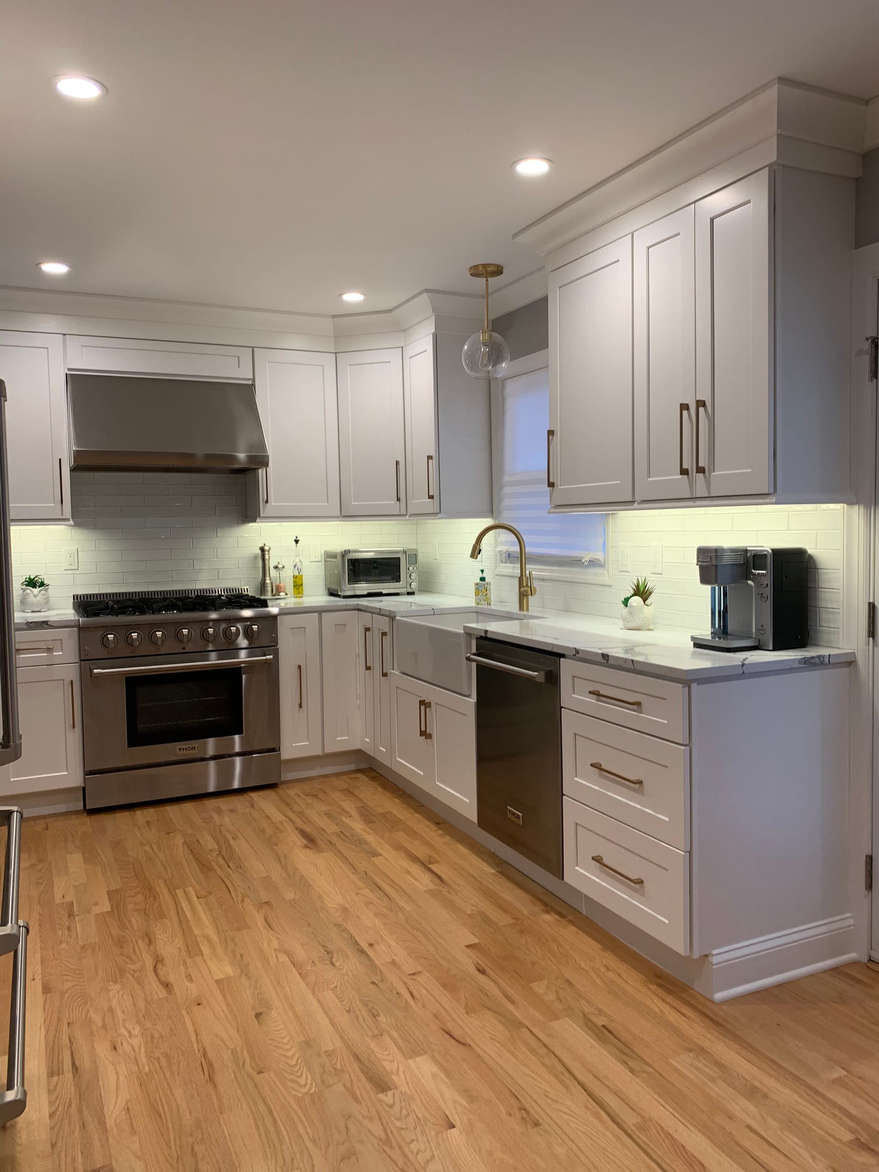 A warm white kitchen with black counters and brass fixtures, seen from the doorway
