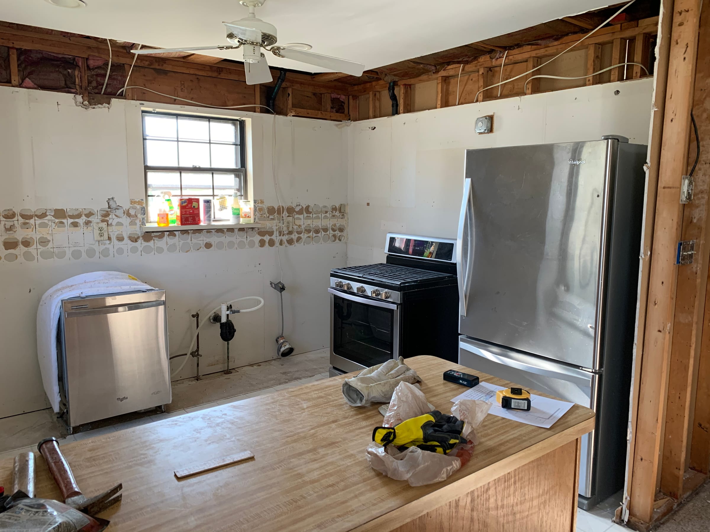 A kitchen stripped to studs and open ceiling partway through a renovation